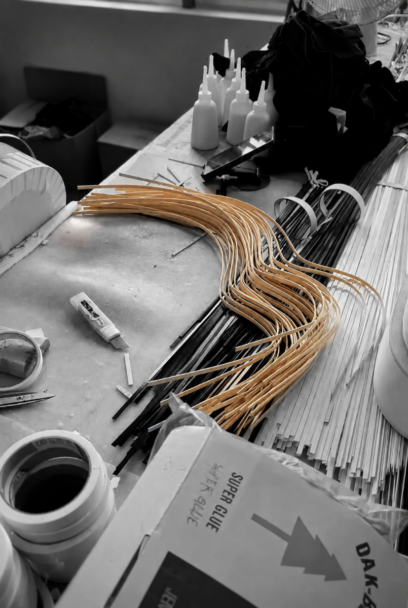 Curved wooden edging strips and straight lengths of light and dark trim on a workshop bench