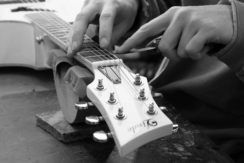 A Lindo team member checking an acoustic guitar at the workshop bench.