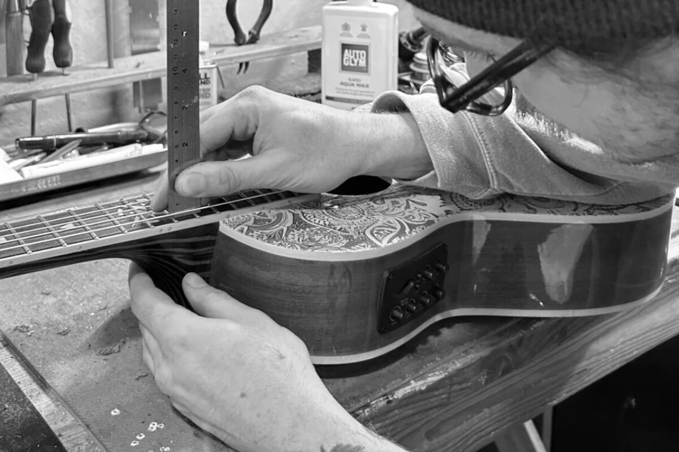 String height being measured on a Lindo acoustic guitar in the workshop.